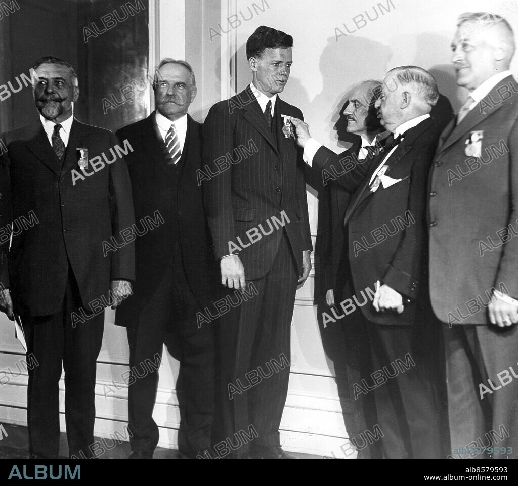 Orig. bildtext... LINDY RECEIVES ORTEIG PRIZE MEDAL. New York. Colonel Walter Scott, head of the Orteig Prize Trustees, is shown here pinning the Trustee's medal on Colonel Charles A. Lindbergh after the air hero had received the $25.000 prize check, which was posted by Raymond Orteig, as a prize for the first man to complete a non-stop New York to Paris flight. Mr. Orteig is shown standing in the centre between Col. Scott and Col. Lindbergh. The ceremonies took place at the Hotel Grevoort. Anm. Charles Augustus Lindbergh, 1902-1974, amerikansk flygare. Den 20-21 maj 1927 genomförde han den första ensamflygningen över Atlanten i flygplanet Spirit of St. Louis. persons: Charles Lindbergh ;Walter Scott ;Raymond Orteig sites: NEW YORK ;USA.