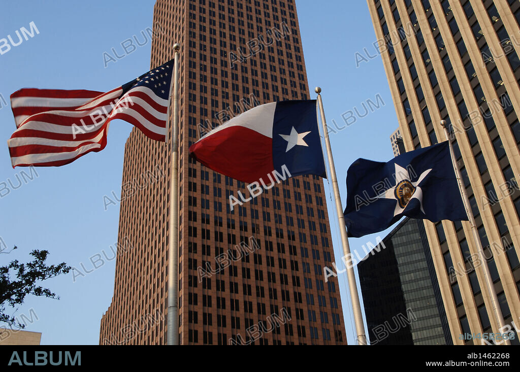 United States of America, State of Texas, Houston. Downtown. Flags of the United States, the State of Texas and the city of Houston. In the background, view of the TC Energy Center, formerly known as Bank of America Center. Postmodern skyscraper completed in 1983. It was designed by architects Philip Johnson and John Burgee.
