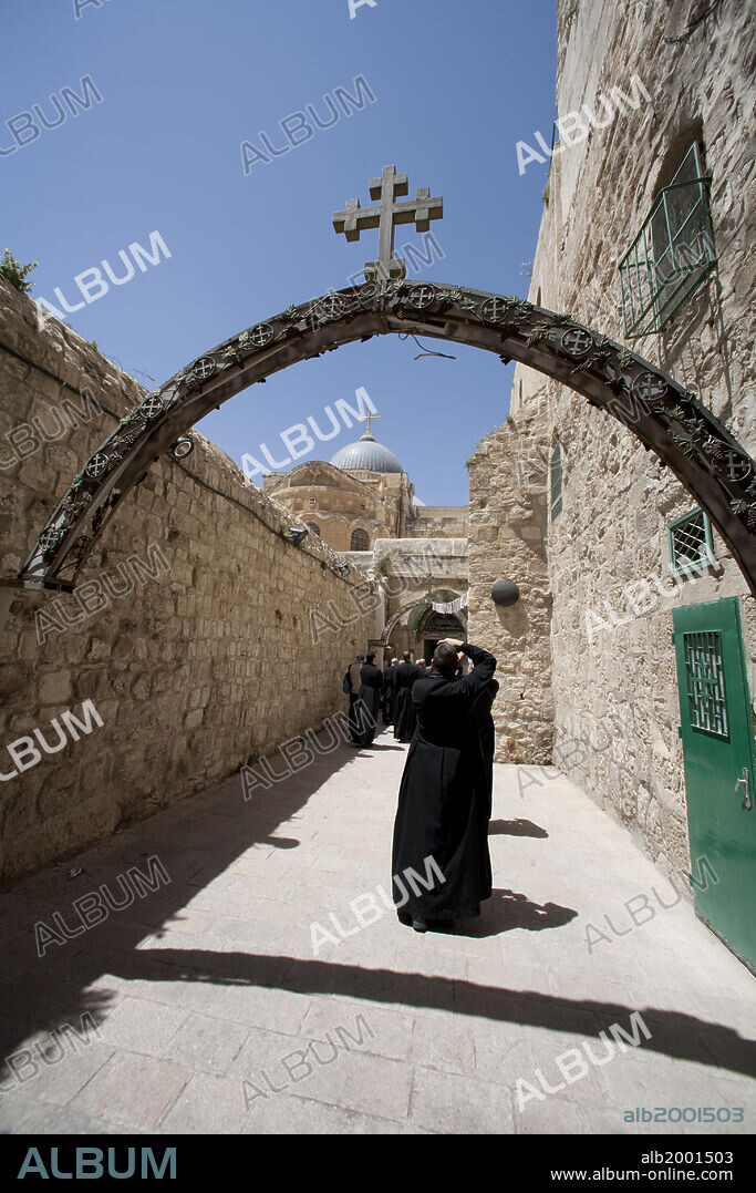 The Via Dolorosa (Latin for "Way of Suffering") is a street within the Old City of Jerusalem, where according to tradition Jesus walked, carrying the cross, on the way to his crucifixion. There are 14 Stations of the Cross along the route, which ends inside the Church of the Holy Sepulchre. At the Ninth Station of the Cross, a Roman pillar, embedded in the wall to the right and signified by a black disc, marks the site of Jesus' third fall. The entrance to the Church of the Holy Sepulchre is seen in the background.
