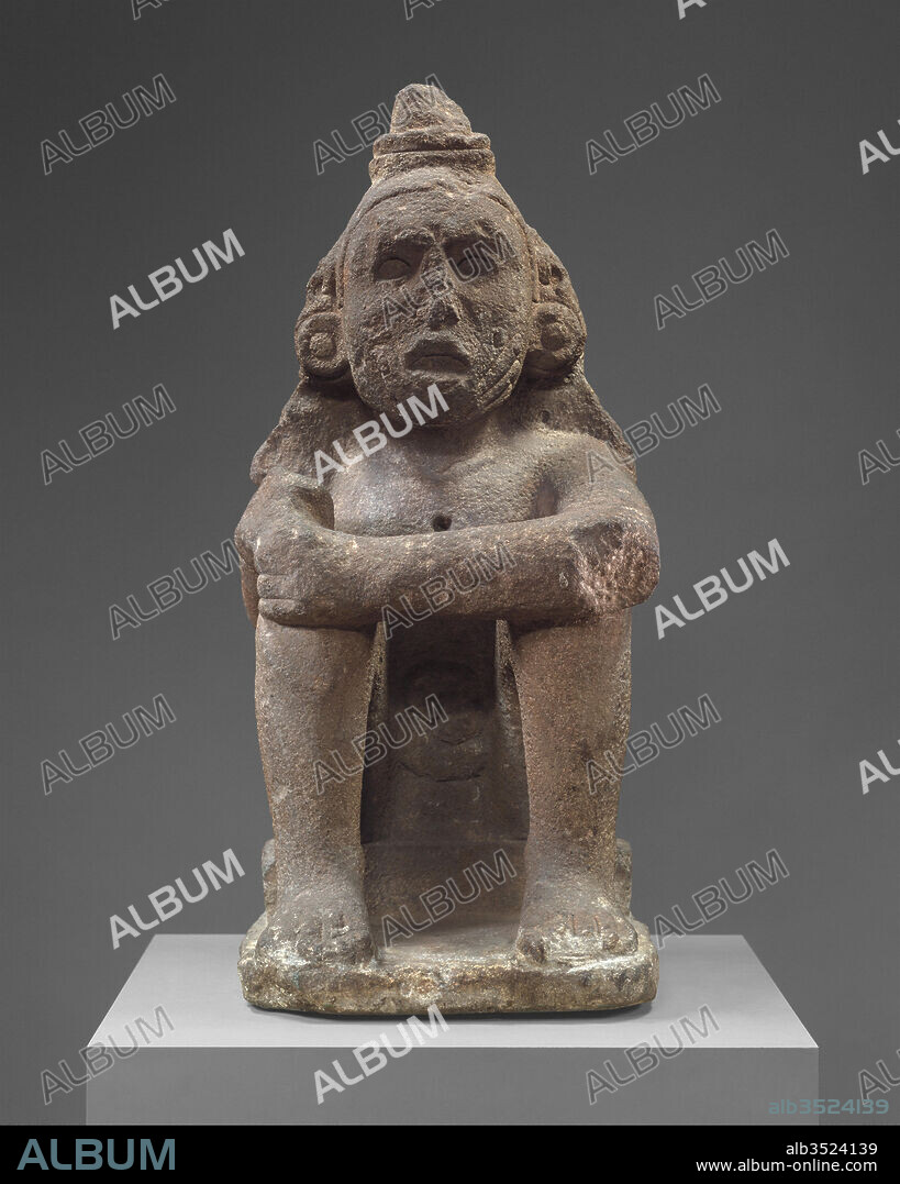 Seated Deity (Macuilcoatl), 15th–early 16th century, Mexico, Mesoamerica, Aztec, Basalt, Overall: 28 1/2 x 12 1/2 in. (72.39 x 31.75 cm), Stone-Sculpture, This sculpture depicts a seated male with his legs drawn up to his chest. His posture is straight and open with his left forearm resting across both knees. The figure’s right hand, which was likely broken in antiquity or during the early Colonial period, is modeled around a small void.