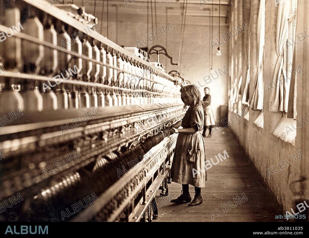 Entitled: "Sadie Pfeifer, 48 inches high, has worked half a year. One of the many small children at work in Lancaster Cotton Mills. Location: Lancaster, South Carolina." Cotton mills were designed to move cotton through a precise series of production processes that separated, straightened, and twisted cotton fibers, combined them into yarn, then wove the yarn into cloth. Workers directed four or more slivers through a series of rollers in the head of a drawing frame, where they were combined in a single strand. As bobbins on the spinning frames filled with thread, doffers replaced them with empty ones. The spinner's job was to move quickly up and down a row of machines, repairing breaks and snags. Child labor refers to the employment of children in any work that deprives children of their childhood, interferes with their ability to attend regular school, and that is mentally, physically, socially or morally dangerous and harmful. Photographed by Lewis Hine, November 30, 1908.
