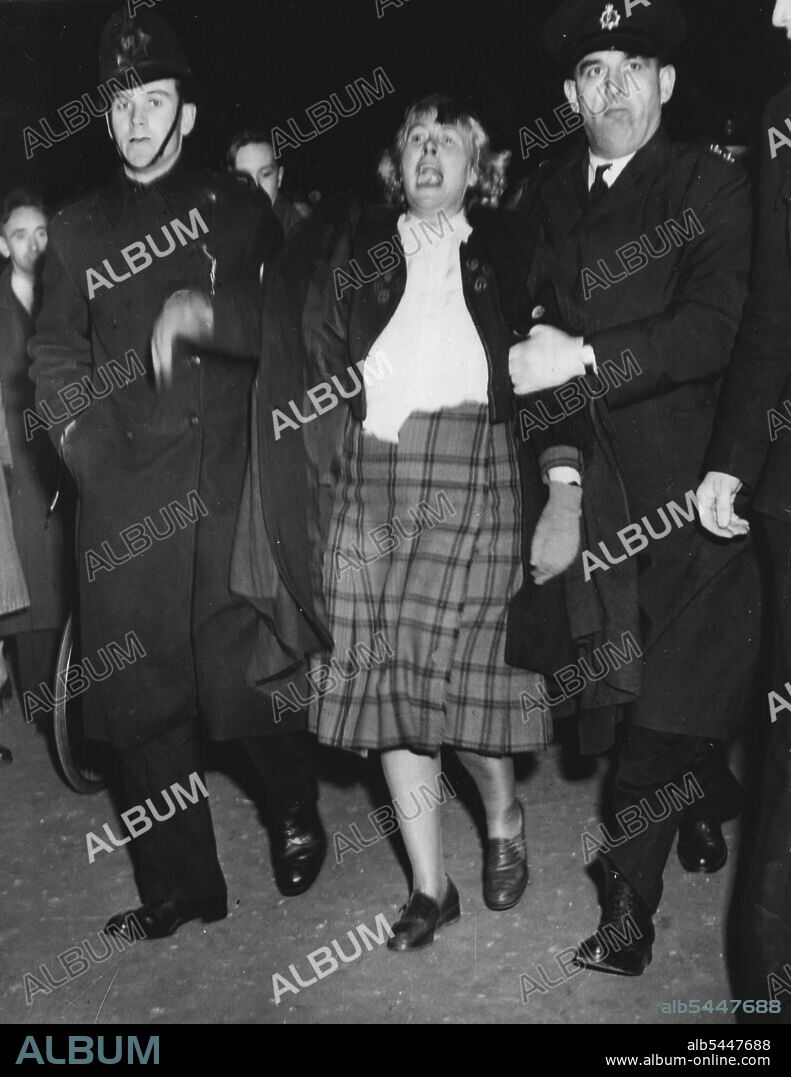 Wendy - Protesting - Is Led Away -- Police Stop Meeting Demanding Return Of 'Stone' -- protesting strongly, Miss Wendy Wood, 57-year-old leader of the Scottish Patriots' Leagna is lead away by Police after they had stopped her form speaking at a meeting in Trafalgar Square to demand the return of the stone of Destiny - the Coronation stone to Scotland. A big crowd of Scots, in London for the England V Scotland international football match at Wembley, gathered for the meeting, banned by the olice as they had not been given 48 hours notice of it. April 14, 1951.