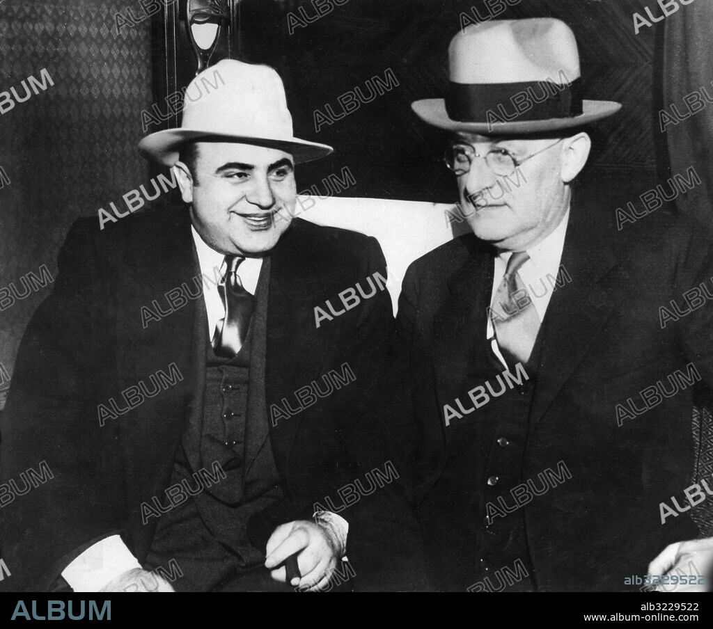 Orig. bildtext... AL CAPONE LEAVES CHICAGO FOR FEDERAL PRISON. Al Capone, The Chicago gangster chief, who has been an inhabitant of the County Jail at Chicago for some time, Was recently removed to the Federal Prison at Atlanta, Georgia, where he is to serve a term of eleven years for the evasion of the Federal Income Tax. O.P.S. Al Capone with United States Marshal Laubenheimer in the compartment of the train which took him to Atlanta Georgia. Judging by his expansive smile, he does not seem to be worrying much. Anm. Gangsters Tågkupé Skattefusk CD123 Se även XAC489 persons: Al Capone sites: USA.
