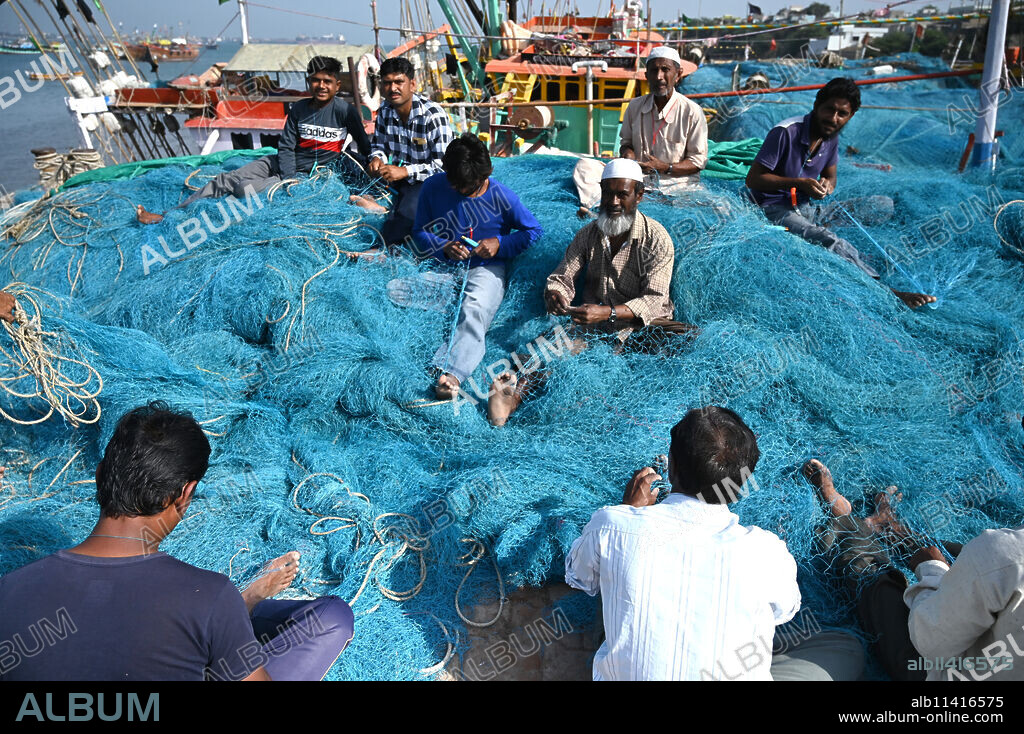 Fishing nets being mended by Muslim fishermen on the quay at Bet Dwaraka island, Dwarka, Gujarat, India, Asia.
