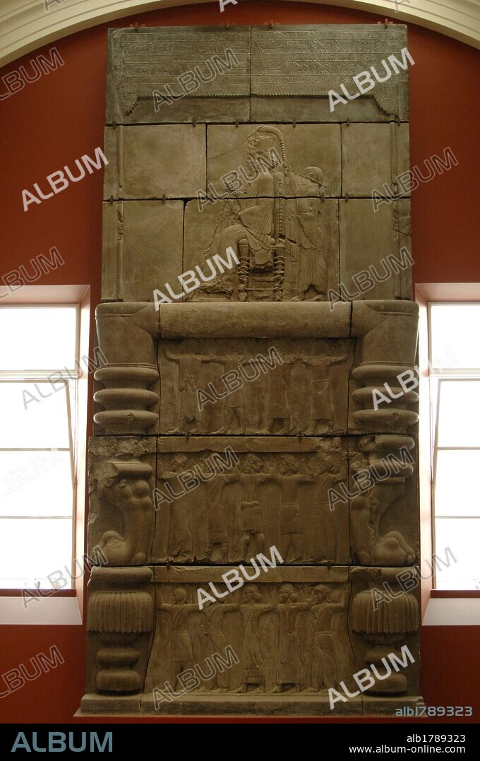 ARTE PERSA. DINASTIA AQUEMENIDA. PERSEPOLIS. S. VI-V a. C. PALACIO DE DARIO I (522-486 a. C.). Detalle de una puerta de entrada a palacio construida entre 470-450 a. C. La escena representa al REY DARIO SENTADO EN UN TRONO SOSTENIENDO UN CETRO Y UNA FLOR DE LOTO CON UN SIRVIENTE A SUS ESPALDAS MIENTRAS OTROS SOSTIENEN AL REY DISPUESTOS EN LAS TRES FILAS INFERIORES. Copia del s. XIX del original conservado en su lugar de orígen (Irán). Museo Británico. Londres. Inglaterra. Reino Unido.