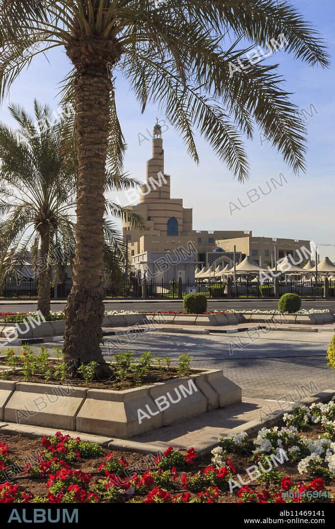 Palm trees and flower beds along Al-Corniche, waterfront promenade, with Qatar Islamic Cultural Centre, Doha, Qatar, Middle East.