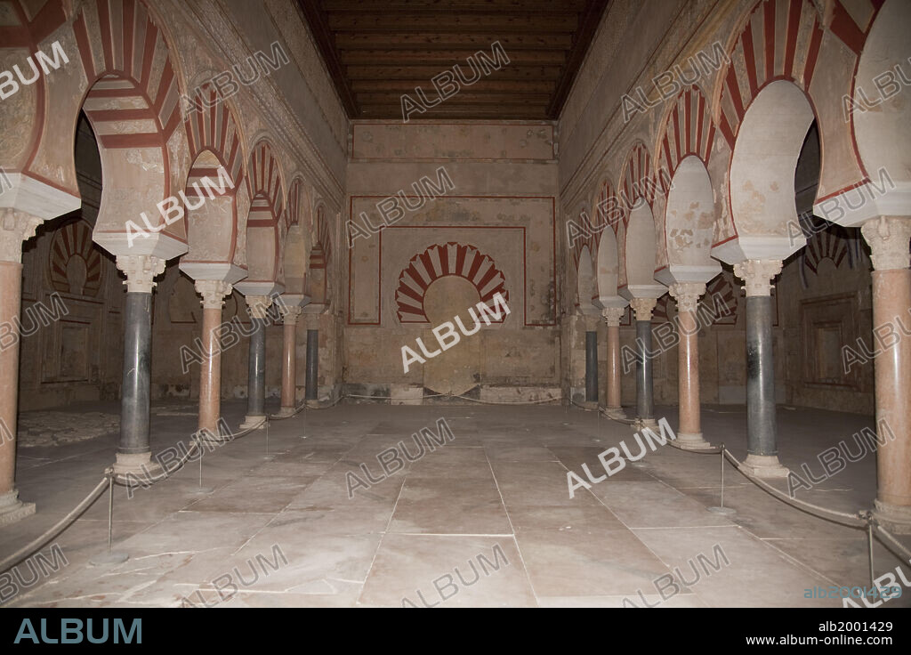 When Abd al-Rahman proclaimed himself Caliph in 929, he founded the palatial city of Madinat al-Zahra as his personal residence and capital of the new Caliphate state. The architecture of the palace was meant to serve as a magnificent representation of the sophisticated protocol that accompanied the caliph's high dignity of position. This is expressed in the splendor of the Hall of Abd al-Rahman III, with its position opening out onto a majestic garden, its basilica design with three naves, and the rich and profuse bas-relief arabesque decoration that covered its walls. Both sides of the central aisle are bordered by horseshoe arches, supported by columns of alternating colors. On the far wall there is a blind horseshoe arch, before which the caliph presumable sat for formal audiences.