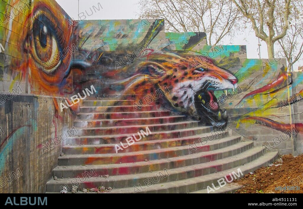 Pintura de un ojo grande y cabeza de tigre rugiendo sobre muro y escalinata, graffiti mural, Plaza de las Glorias; Distrito San Martin, Barcelona en 2014.