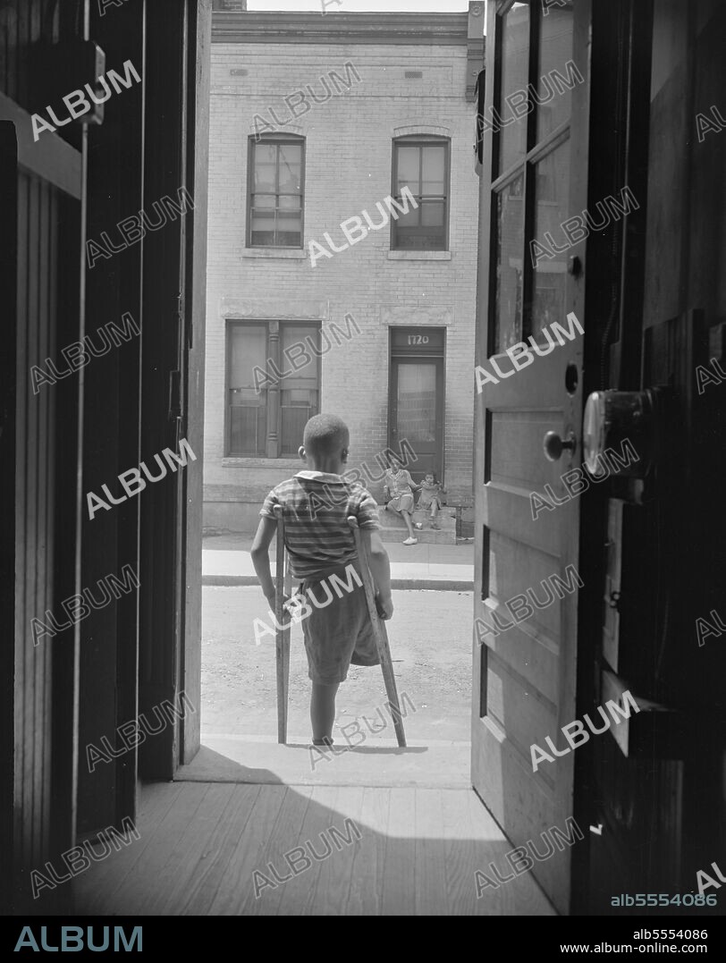 GORDON PARKS. Washington, D.C. Young boy standing in the doorway of his home on Seaton Road in the northwest section. His leg was cut off by a streetcar while he was playing in the street.