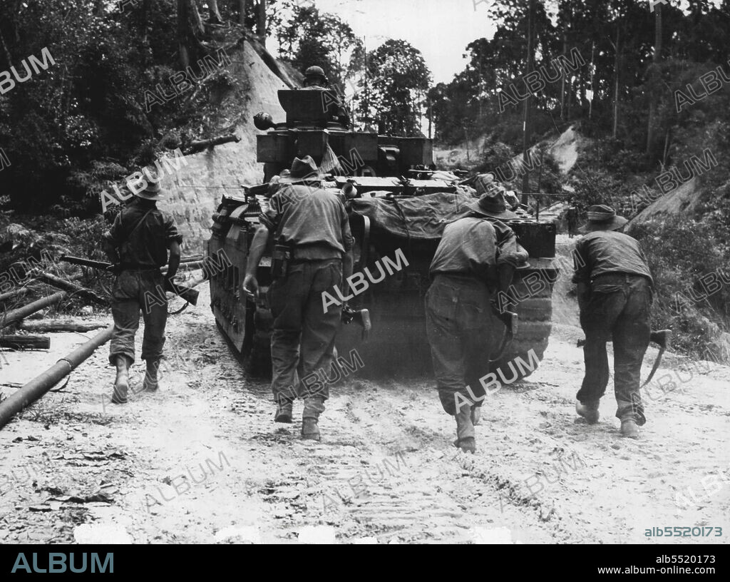 Engineers of 2/48th Australian Infantry Battalion crouching behind Matilda Tank of "C" Squadron, 2/9th Australian Armored Regiment moving up to Sykes Feature to support troops already in action but weakened owing to casualties. May 06, 1945. (Photo by Australian War Memorial Canberra, A.C.T.).