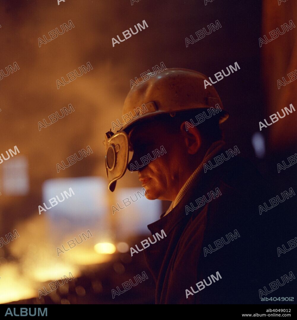Steelworker, Newton Chambers, Chapeltown, Sheffield, South Yorkshire, 1971. A steelworker lit by the glow of the furnace. George Newton and Thomas Chambers entered into a partnership in 1789 that would result in the founding of one of England's largest industrial companies of that era, Newton, Chambers & Co. During the Second World War the company built the Churchill Tank and the company also owned other well known brands such as Redfyre and Izal.
