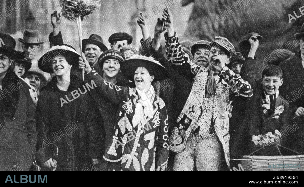 Pearly king and queen in high spirits, London, 1926-1927. Cockney 'Pearly kings' (originally costermongers - fruit and vegetable sellers), wore suits covered in mother-of-pearl buttons. Illustration from Wonderful London, volume I, edited by Arthur St John Adcock, published by Amalgamated Press (London, 1926-1927).