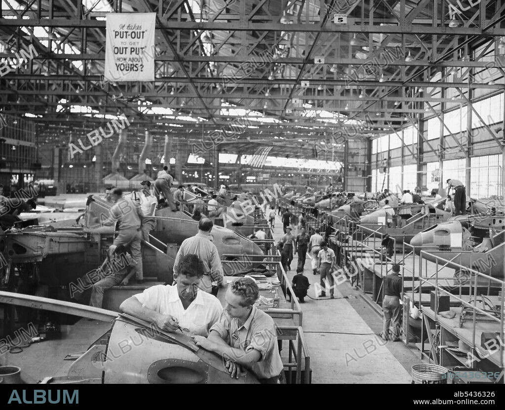 Wants To Advance -- Kenneth McMahon, (Right) talks over a detail of the manufacture of airlines at the Lockheed plant, Burbank, Cal., with Todd Oviatt, his superior. He hopes by successive "Upgradings" eventually to step into a supervisor's shoes. That's why he has been spending a couple of nights a week in study. Scene inside one of the great construction hangars of the Lockheed Aircraft Corporation at Burbank, California. July 20, 1941. (Photo by Associated Press Photo).