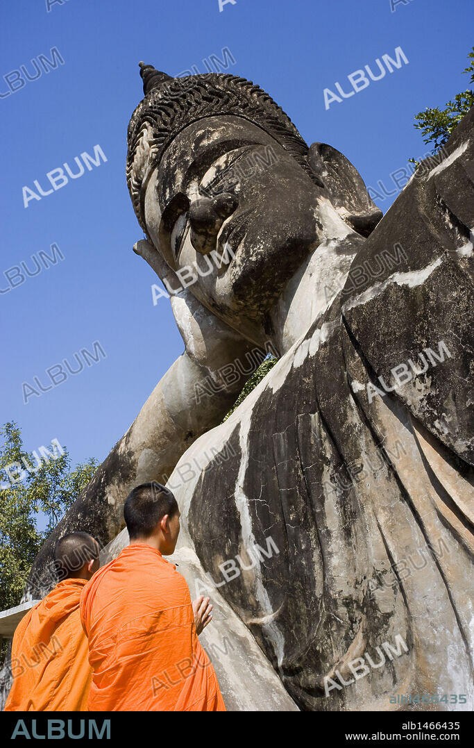 MONJES BUDISTAS junto a la ESTATUA DE BUDA RECLINADO. PARQUE DE BUDA ("BUDDHA PARK"). Cercanías de Vientiane. Laos.