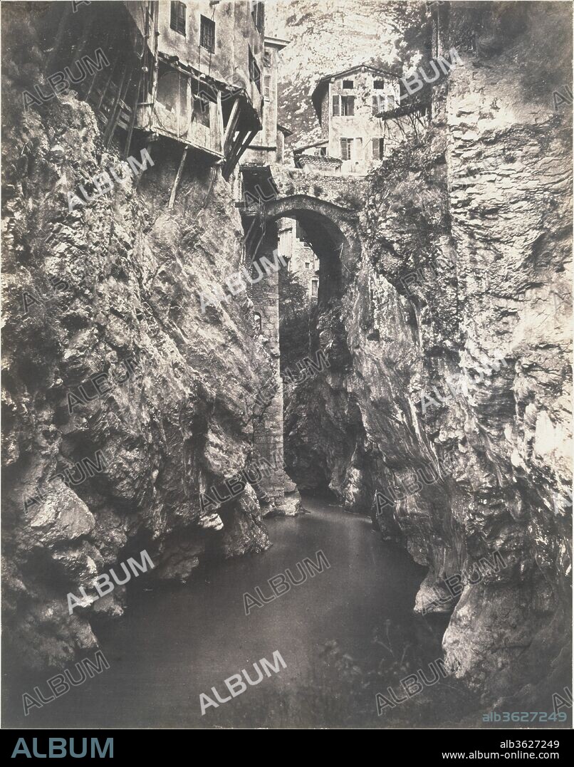 EDOUARD BALDUS. Pont en Royans. Artist: Édouard Baldus (French, born Prussia, 1813-1889). Dimensions: Image: 43.2 x 33.9 cm. (17  x 13  3/6  in.). Date: ca. 1859.
The cliff-bound town of Pont-en-Royans-where residents lowered buckets and nets into the river from their cantilevered houses-was a well-known destination for those visiting the picturesque sites of France. Baldus pushed the town to the very top of his picture and banished the horizon altogether, focusing on the rough rock surfaces of the ravine with a realism rivaled only by Courbet.
