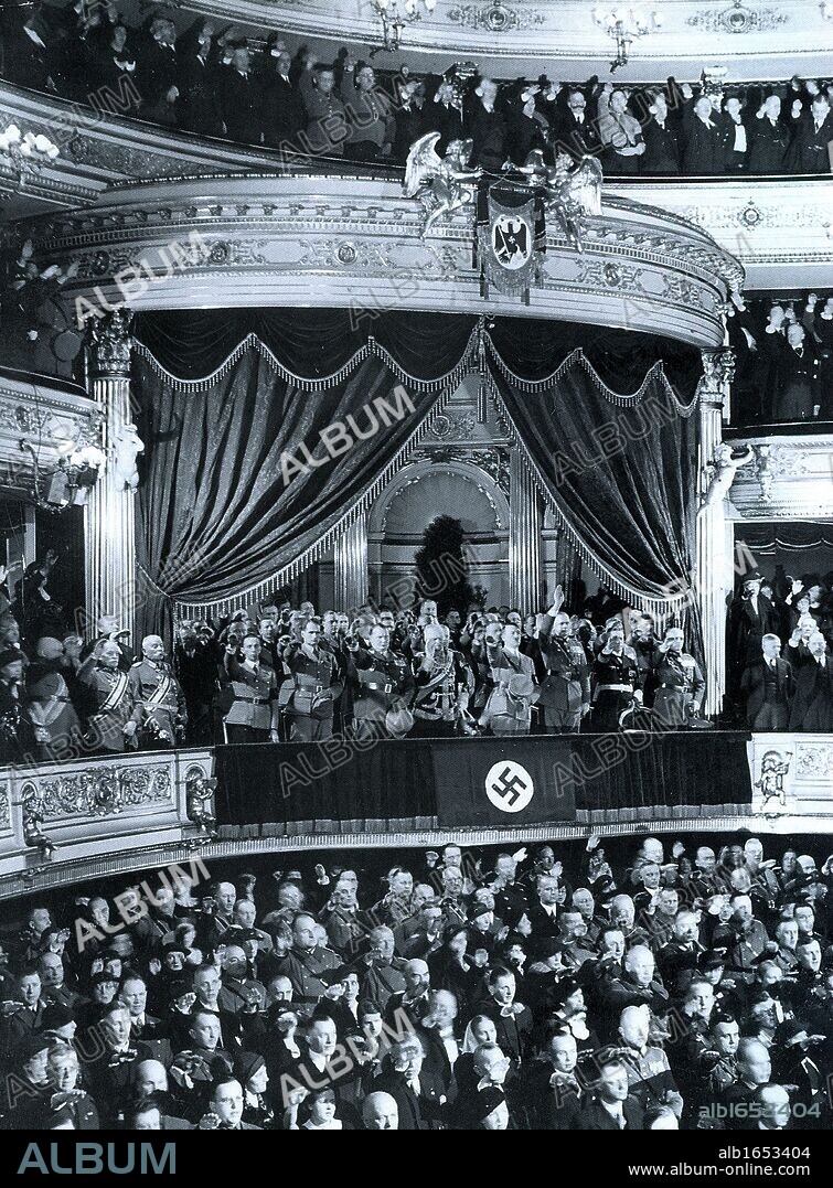 Chancellor Adolf Hitler is greeted by an audience in a theatre in Germany c1935. Key Nazi leaders attending are seen in the State Official Box. Left to right: Josef Goebbels, Rudolf Hess, Herman Goring, Field Marshall Von Mackensen, Adolf Hitler, General Keitel and Admiral Raeder.