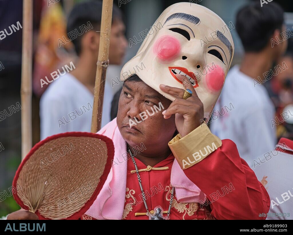 Thailand: A man lifts his Chinese mask in a procession through the streets of Phuket Town, Phuket Vegetarian Festival (Nine Emperor Gods Festival). The Vegetarian Festival is a religious festival held annually on the island of Phuket in southern Thailand. It attracts spectators because of some of the unusual religious rituals performed. Many devotees will slash themselves with swords, pierce their cheeks with sharp objects and commit other painful acts. The Nine Emperor Gods Festival is a Taoist celebration beginning on the eve of 9th lunar month of the Chinese calendar.