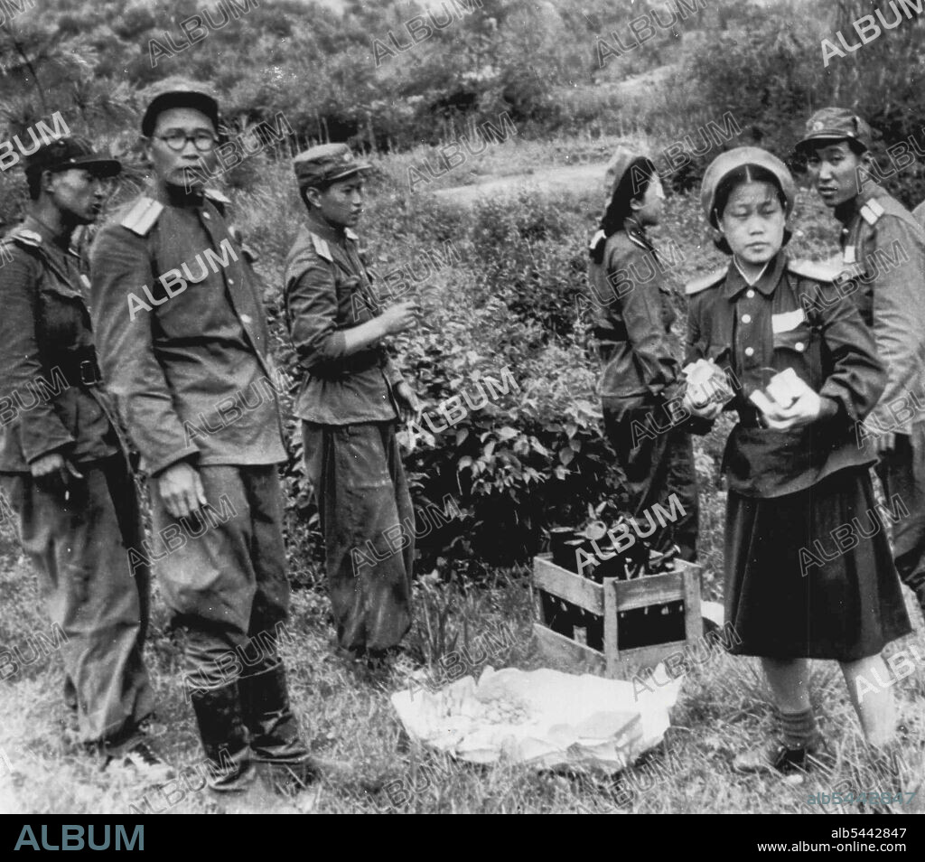 Cigarettes for Negotiators -- Two North Korean girls in uniform get ready to pass out candy, cigarettes and beer to members of UN party in Kaesong July 11 as North Korean soldiers watch. Negotiations, suspended the next day when Reds stopped a UN convoy, were resumed today after communists agreed to remove armed guards from Kaesong and to let correspondents in the area. July 15, 1951. (Photo by AP Wirephoto).