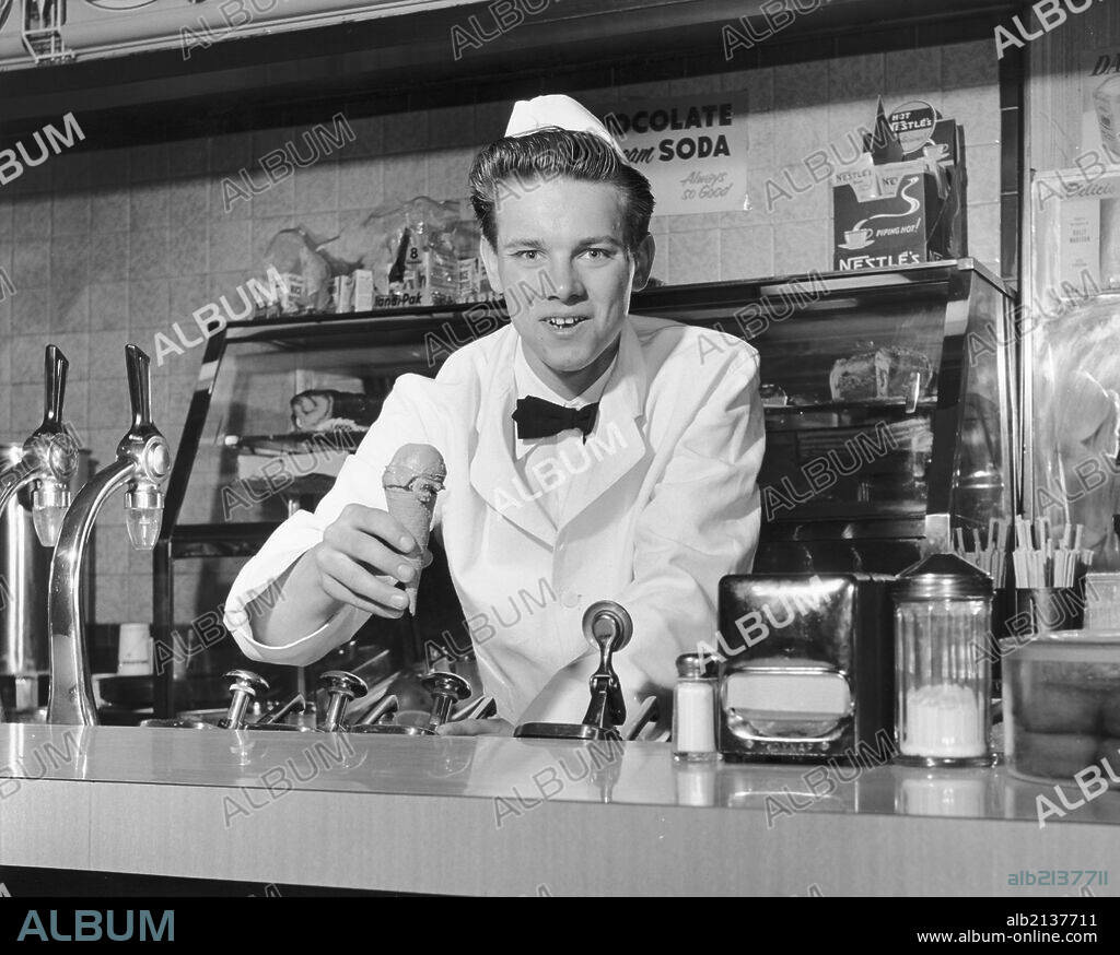 Soda jerk holding ice cream cone, 1960s.