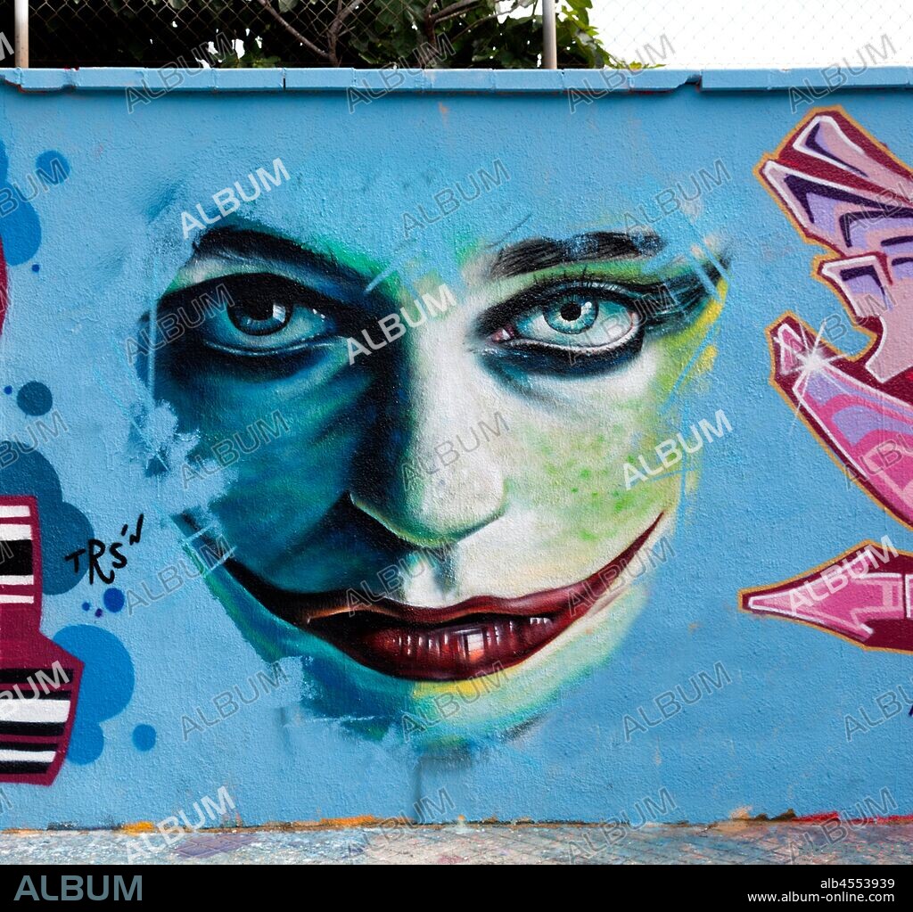 Pintura de rostro de mujer maquillada con los labios pintados estirando la boca, graffiti mural, calle Agricultura, Poblenou, Distrito San Martin, Barcelona en 2016.