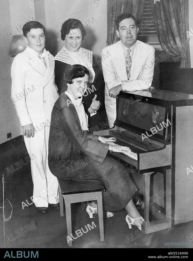 Then the Longs Visited New York -- New York-here's the family of Senator Huey P. Long of Louisiana, photographed when they visited here July 25, and the senator took time out to show the town how to make a Gin Fizz. At the Piano is daughter Rose; in back, left to right, Palmer Long, Mrs. Long and the "Kingfish," who was shot and seriously wounded in the Baton Rouge, La., state house September 8. September 9, 1935. (Photo by Associated Press Photo).