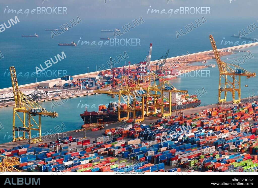 BARCELONA, SPAIN, APRIL 17, 2019: View of cargo ship unloading in Barcelona port terminal with straddle carrier trucks moving shipping containers.