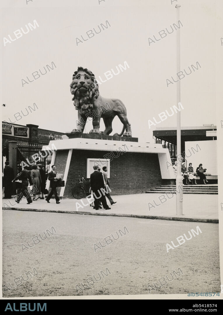 JR UPPINGTON. South Bank Lion, York Road, Lambeth, Greater London Authority, 1951. The South Bank Lion on a plinth outside the York Road entrance of Waterloo Station, viewed from the west. The South Bank Lion, or Red Lion, stood on the parapet of the Lion Brewery on the south bank of the River Thames near Hungerford Bridge. The sculpture was created in 1837 by William Frederick Woodington. The lion is formed from separate parts, visible in this photograph, using Coade stone. The Lion Brewery on Belvedere Road was demolished in 1949, having been damaged by fire in 1931; the site was used as the South Bank Exhibition for the Festival of Britain in 1951. The sculpture was removed before the demolition of the brewery and, having likely been painted red previously, was restored and repainted. It was positioned on a plinth outside the York Road entrance of Waterloo Station until 1966, when it was moved to the east end of Westminster Bridge in Lambeth and was stripped of its red paint. The sculpture is Grade II* listed.
