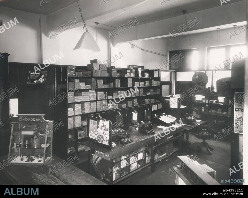 Photograph, Shop Interior, Perth, Western Australia, 1935, Black and white photograph of the Kodak Australasia Pty Ltd shop interior at 662 Hay Street, Perth. It features the working area behind the front counter, including a workstation with two typewriters, a shelf full of photographic paper and film products, various glass fronted retail cabinets and a window leading outside. This is one of 3 photographs of the Perth facilities, printed at.