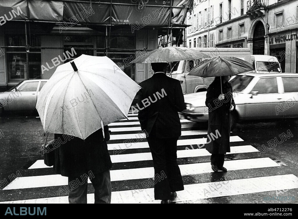 Passage pieton, passants sous leur parapluie, Boulevard Richard Lenoir a Paris, 1980. Scene de rue, Vie quotidienne, dans la ville, Paris , annees 80. Photographie JEAN POTTIER. Credit photo JEAN POTTIER/KHARBINE TAPABOR.
