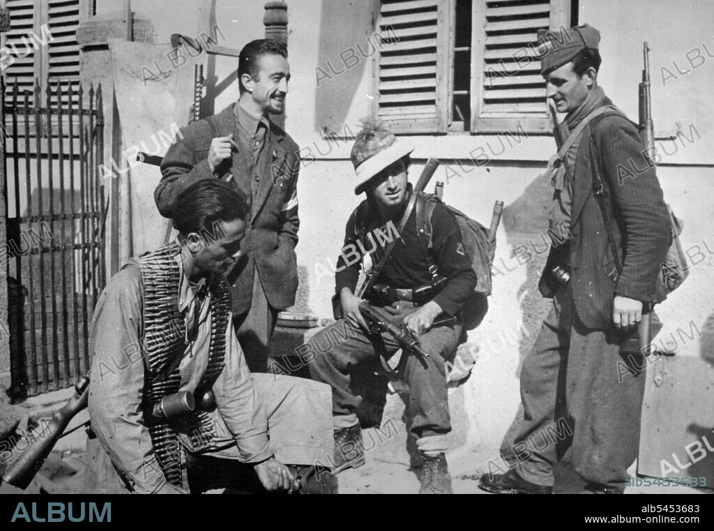 Italian Patriots Check Their Weapons In Liberated Loiano
An Italian patriot checks his machine gun while three of his comrades, also heavily armed, stand by and converse in the liberated communications center of Loiano. Patriots played a major part in freeing the town, which was completely cleared of the enemy by the Allied Fifth Army under U.S. Lieutenant General Mark W. Clark on Oct. 6, 1944. Loiano is only 14 miles (22 Km.) south of Bologna, a major communications and industrial city guarding remaining German positions in northern Italy. November 15, 1944. (Photo by  U.S. Officer of War Information Picture).