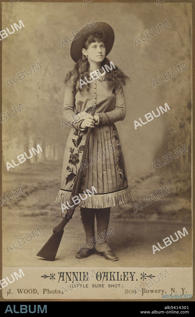 Annie Oakley (August 13, 1860 - November 3, 1926) was an American sharpshooter and folk hero. She hunted game for a local grocery store, earning enough to pay off the mortgage for her mother's home.  In 1876, Oakley married Frank E. Butler, a top shooter and vaudeville performer. The couple toured with Buffalo Bill's Wild West Show, with Oakley receiving the spotlight and top billing while Butler worked as her manager. She could shoot off the end of a cigarette held in her husband's lips, hit the thin edge of a playing card from 30 paces, shoot distant targets while looking into a mirror, and shoot holes through cards thrown into the air before they landed. John Wood, 1885 (cropped and cleaned).