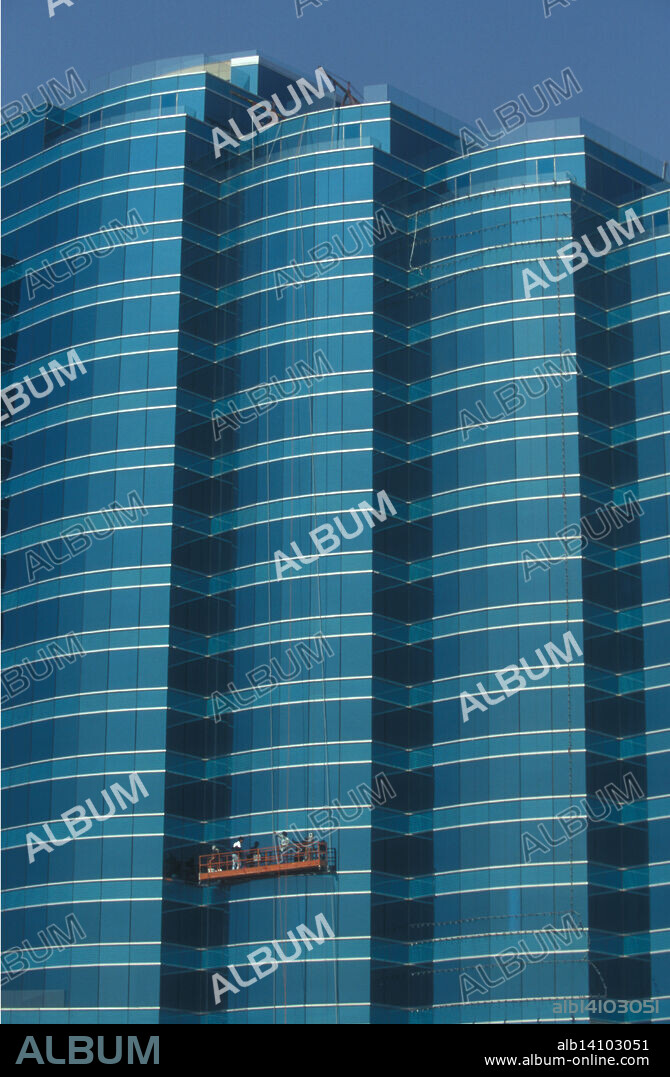 Grúa/brazos colgantes con operarios dentro de una góndola para la limpieza de edificios altos. Distrito Central de Hong Kong.