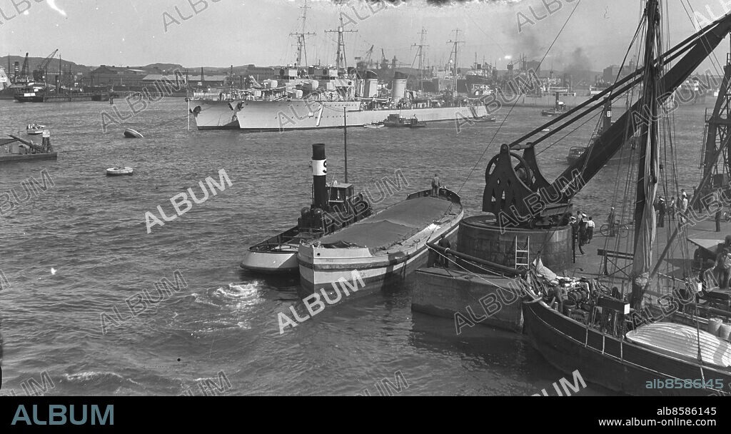 Göteborg 1938-08 - Bogserbåt och stor lyftkran - på redden ligger två krigsfartyg *** Local Caption *** GT Låda 1938-augusti-01. KAMERAREPORTAGE.