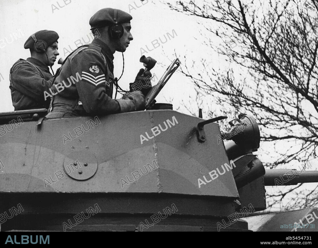 The Modern Cavalry: A gunner operator (left) and a Section Commander at the ready in an Armored car, at a battle school in England. The Reconnaissance Regiment, one in each Infantry Division, is the modern equivalent of Divisional Cavalry. Very largely on their information, every General commanding troops in the field forms his plan for battle. May 1, 1944. (Photo by P.N.A.).