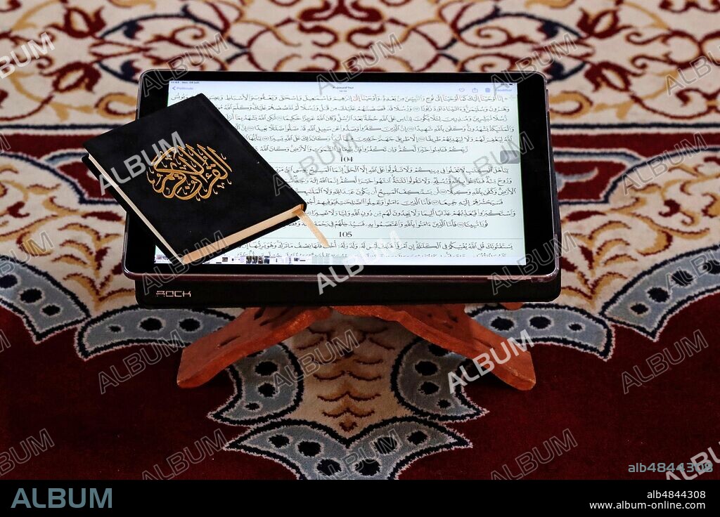 Digital Quran on a tablet and traditional Holy Quran.