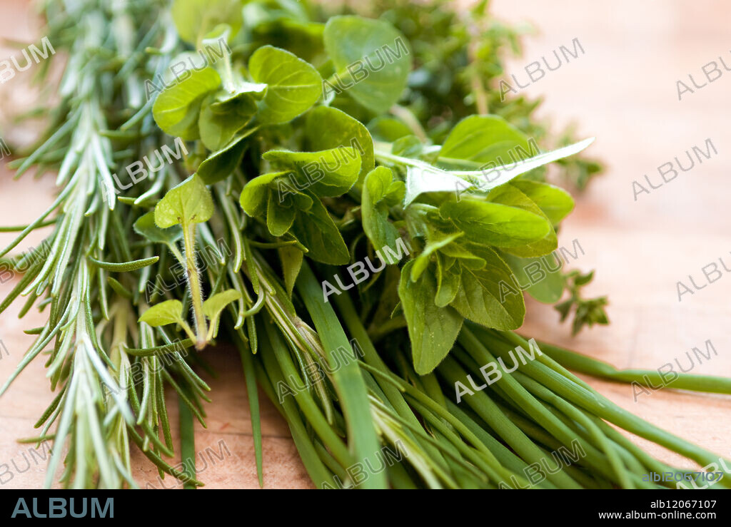 Bunch of fresh mixed herbs on wooden chopping board. credit: Marie-Louise Avery / thePictureKitchen / TopFoto.