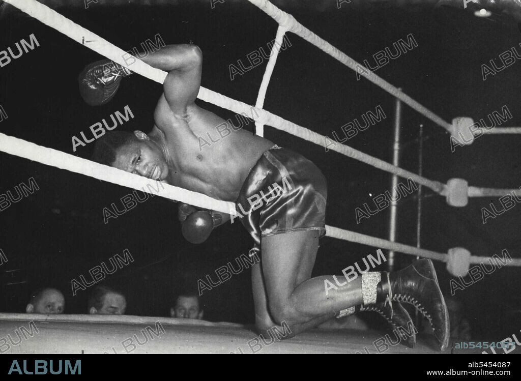Cockell K.O.'s Marshall in First Round - Lloyd Marshall, knocked out, hangs through the ropes at Harringlay tonight.Don Cockell, British cruiser weight boxing champion, knocked out American negro Lloyd Marshall in the first round of their battle in Harringay, London, tonight (Tuesday), treating the fans to two first round knockout spectacles in the fight card. Earlier Randolph Turpin had knocked out Van Dam of Holland in the first round. February 27, 1951. (Photo by Reuterphoto).