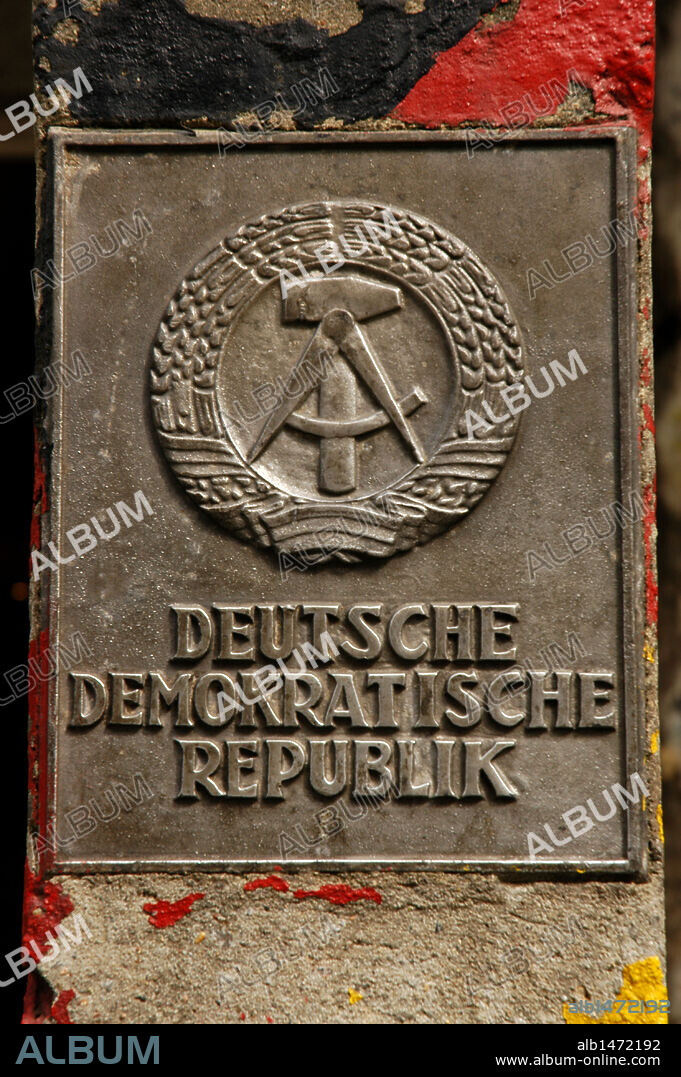 Símbolo de la antigua R. D. A. (República Democrática Alemana) junto a un tramo del MURO DE BERLIN, en el "Haus AM Checkpoint Charlie". BERLIN. Alemania.