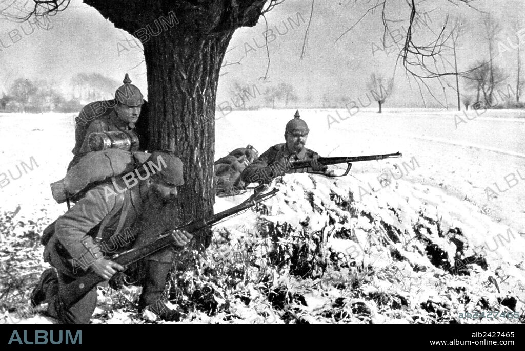 World War I 1914 1918. Invasion of Belgium. German soldiers with the typical spiked helmet advance on a ground covered by snow during the first winter of the war of 1914.