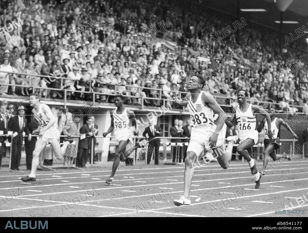 FINLAND HELSINGFORS 1952-07-23.. Löparna springer i mål i finalen på 200 m. vid de olympiska sommarspelen 1952. Andrew Stanfield (USA), 983, vinner på tiden 20,7 sek. (olympiskt rekord) före Thane Baker (USA), 984, tvåa på 20,8 sek., James Gathers (USA), 985, trea på 20,8 sek., och McDonald Bailey (Storbritannien), 166, fyra.. Foto: Olympic World Photo Pool / AB Text & Bilder / SVT / Kod: 5600. Mapp: 200 m (O.S. -52) I:286c. Vinnare Segrare.