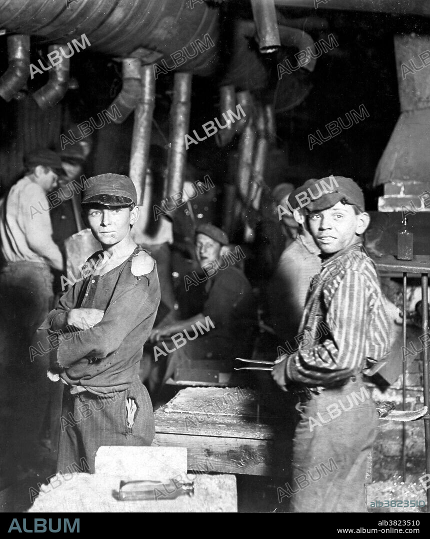 Entitled: "Glass works. Midnight. Location: Indiana." There were four main jobs in the glass factories that used boys as a majority of the labor. The boy who opens and closes the iron mold for the blower was the "holding-mold boy". The second job required the boy to stand beside the presser and receive the tumblers from the large mold was called the "ketchin-up boy". The third job was for the boy who seized the blown or pressed objects with a long iron rod and holds them in the flame of the glory hole was called the "sticker-up boy". The final job was for the boy who takes the finished objects from the finisher to the annealing oven for the final firing of the object and was called the "carrying-in boy". These jobs required long hours and cramped conditions. Photographed by Lewis Hine, 1908.