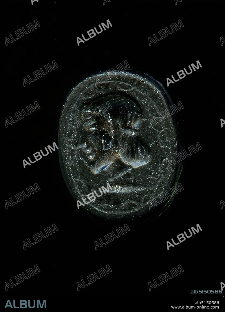 Gem in the shape of a scarab (head of Aphrodite?), Jasper, cut, drilled, Jasper, Total: Height: 1.1 cm; Width: 0.85 cm; Depth: 0.64 cm, Body ornamentation, Glyptic, History of Venus (Aphrodite), Head, Face, Strict style, late archaic, The intaglio in the form of a scarab is pierced. On the underside there is the image field, which shows a female head to the left. Shown is the head of the goddess Aphrodite, which can be found quite similar on coins. An intimated band holds the hair together above the neck. Above the forehead a crown of hair is clearly visible. The mouth is still indicated in the so-called archaic smile, which gives a clue to the dating of the gem to the late archaic period. The goddess wears a pearl necklace around her neck. Unusual is the framing of the picture with an oval as well as an inwardly arched repeat. The base line is reinforced by dots.