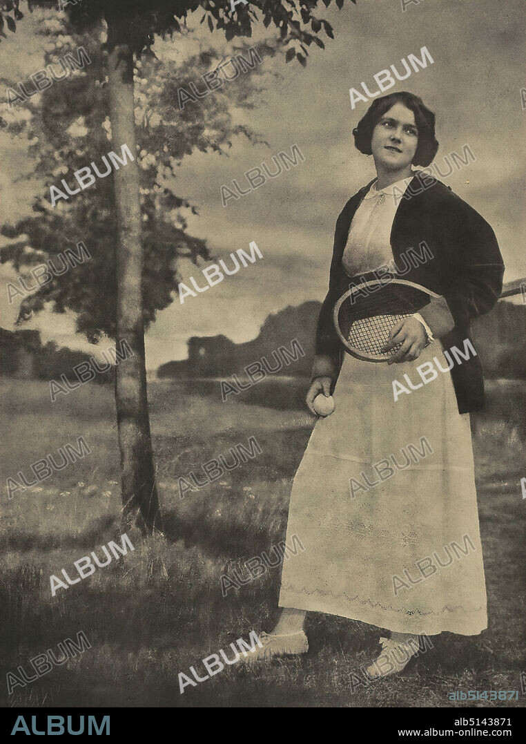 Nicola Perscheid, girl with tennis racket, paper, oil overprint, picture size: height: 49 cm; width: 36,5 cm, signed: recto u. li.: in lead: N. Perscheid, portrait photography, portrait, young woman, girl, nature, meadow, pasture, trees, bushes, dress, sport, games, tennis, tennis player etc, tennis equipment, tennis outfit etc.