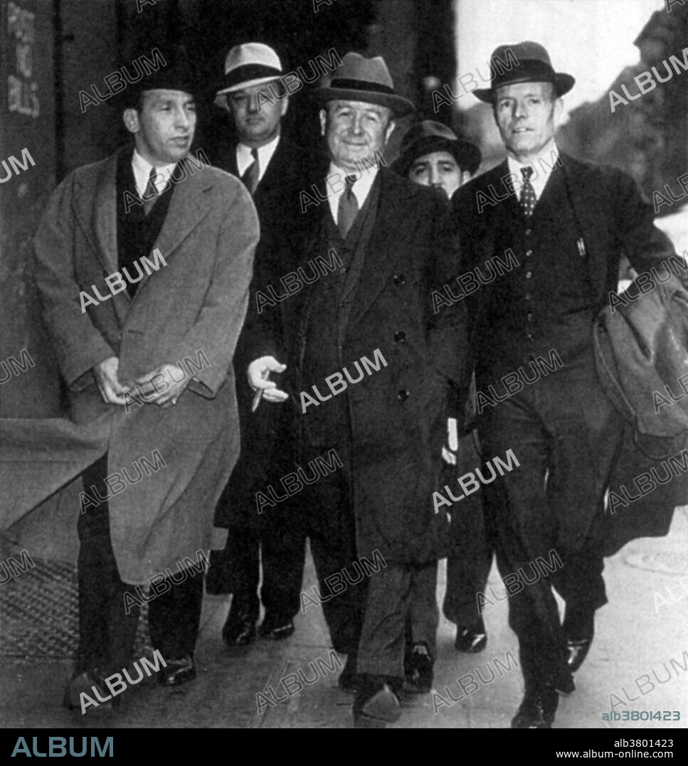 Torrio, center, holding cigar. John "Papa Johnny" Torrio (January 20, 1882 - April 16, 1957) was an Italian-American mobster. Prohibition was established in 1920 which banned the distribution of alcoholic beverages. As the 1920s progressed, Torrio presided over the expansion of the Chicago Outfit as it raked in millions from gambling, prostitution, and now bootlegging. The Outfit controlled the Loop and much of the South Side, but they were intent on seizing the profitable Gold Coast territory from the North Side Gang led by Dean O'Banion. O'Banion's murder sparked a bloody, brutal gangland war between the North Side Gang and the Outfit that eventually chased Torrio out of Chicago. He put forth the idea of the National Crime Syndicate in the 1930s and later became an unofficial adviser to the Genovese crime family. In 1957, Torrio had a heart attack in Brooklyn while sitting in a barber's chair waiting for a haircut. He was 75 years old. No photographer credited, undated.