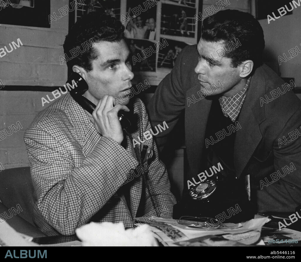 After The Fight Fiasco... Vince Cartier telephone New York. On right is brother Walter. The Cartier brothers, Walter the boxer, and Vince the Lawer, were busy to-day trying to work out what went wrong in last night's fight against Randolph Turpin, in which the referee called a halt after 65 seconds of the second round and disqualified Walter for holding. The board of control meet tomorrow to decide about his share of the purse. March 18, 1953. (Photo by Paul Popper Ltd.).