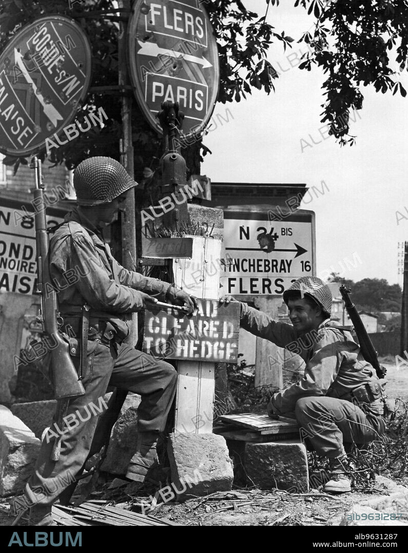 Vire, Paris, France, August 11, 1944 Charles Lynch, Hollsopple, PA and Louis Motto, Cleveland, Ohio, US engineers nail up a sign signifying that the way ahead has been cleared of mines.