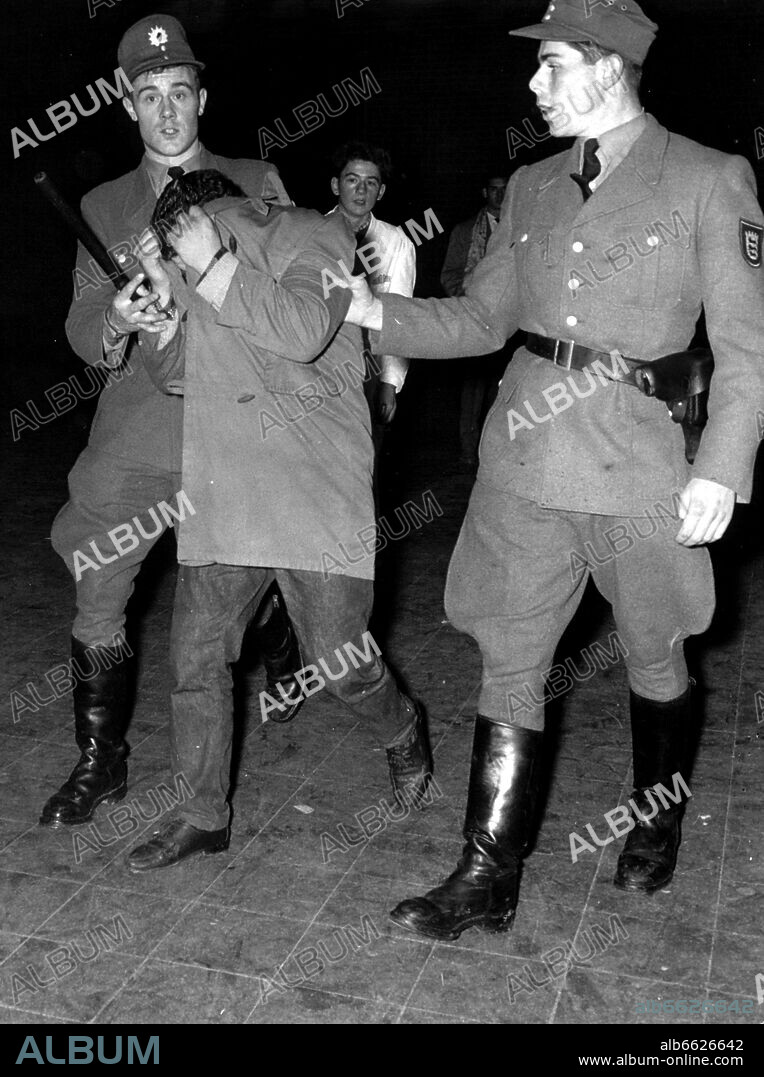 Police men lead a young man off after the Bill Haley-concert on the 29th of October in 1958 in Stuttgart. There had been turmoils during the concert. 29/10/1958