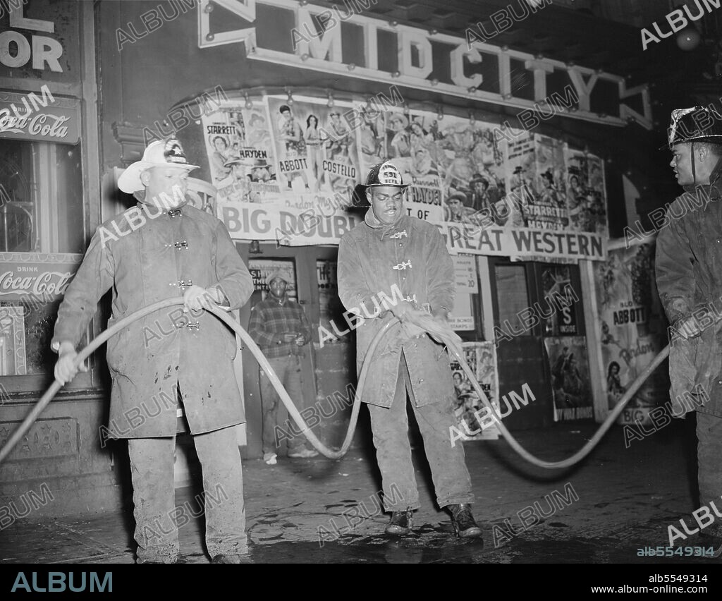 GORDON PARKS. Firehouse Station No. 4. Washington, D.C. Cleaning a hose in front of a theater after a fire. The fireman in the white helmet is a sergeant.