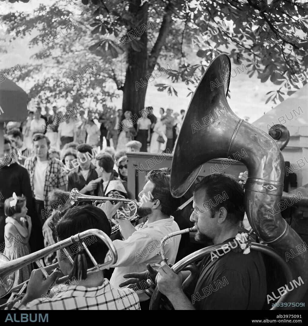 Musicians, Hampstead, London, 1957-1962. A band performing outdoors, with musicians playing a trombone, trumpet, and sousaphone.