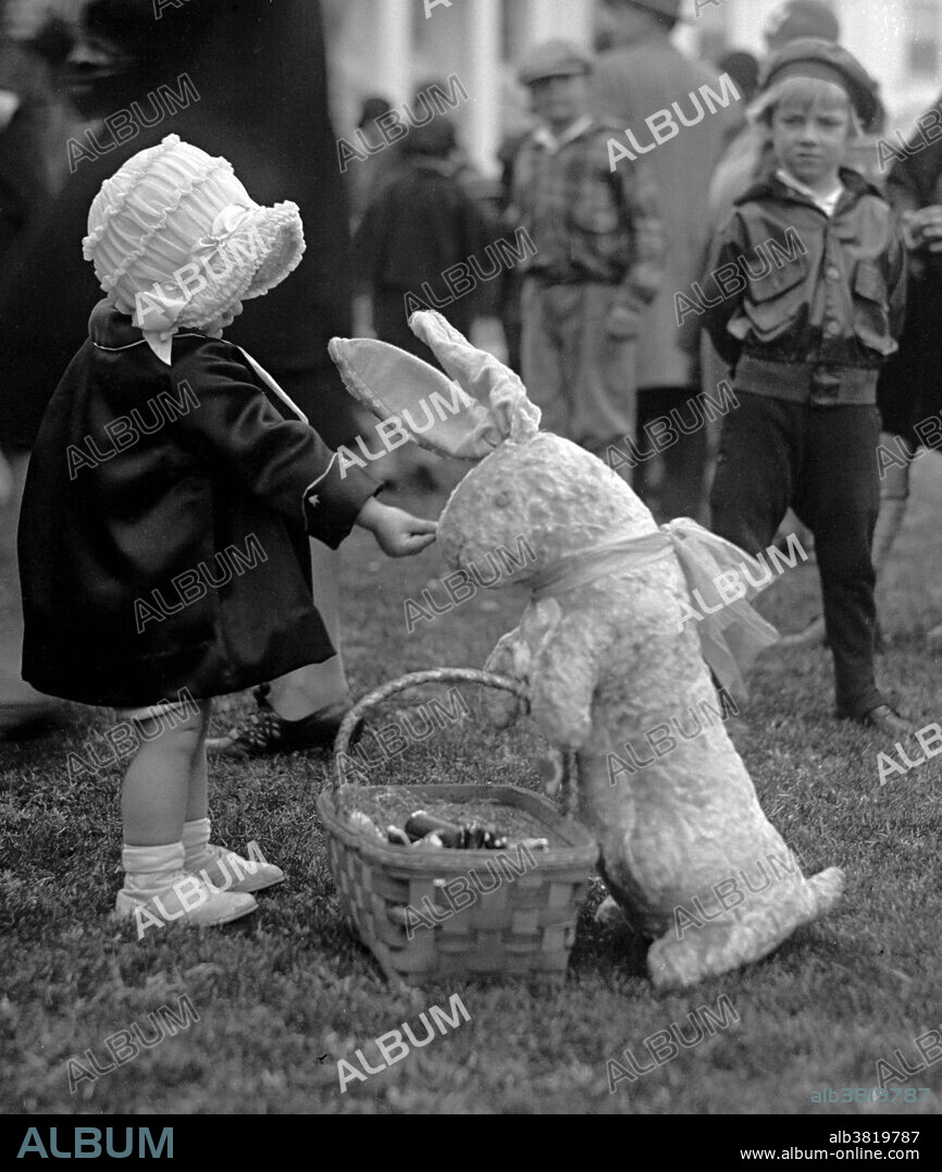 In the United States, the Easter Egg Roll is an annual event, and is held on the White House lawn each Easter Monday for children and their parents. The Egg Roll itself is a race, where children push an egg through the grass with a long-handled spoon. Surrounding events include appearances by White House personalities in Easter Bunny costumes, speeches and book-reading by Cabinet secretaries, and exhibits of artistically-decorated eggs. Many Americans follow the tradition of coloring hard-boiled eggs and giving baskets of candy. The Easter Bunny is a popular legendary anthropomorphic Easter gift-giving character analogous to Santa Claus in American culture. Photographed by the National Photo Company, April 1, 1929.